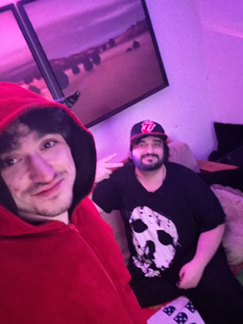 mel in a red hoodie taking a selfie with a friend under purple lights